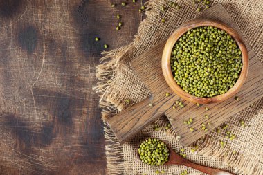 Mung. Kahverengi ahşap bir masada bir kasede yeşil fasulye. Sağlıklı bir diyet için baklagil bitkisi