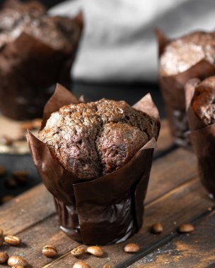 Çörek. Siyah mutfak masasında, tahta servis tahtasının üzerinde çikolatalı kekler. Lezzetli tatlı hamur işleri. Siyah arka planda kahve kekleri.