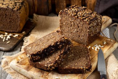 Servis tahtasında ayçekirdeği olan çavdar ekmeği. Tahtadaki tahta kırsal bir masada duran ekmek parçaları. Sağlıklı çavdar ekmeği