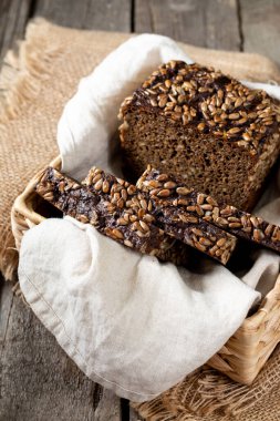 Hasır sepette ayçiçeği tohumlu çavdar ekmeği. Tahta bir kırsal masada sepetteki ekmek parçaları. Sağlıklı çavdar ekmeği