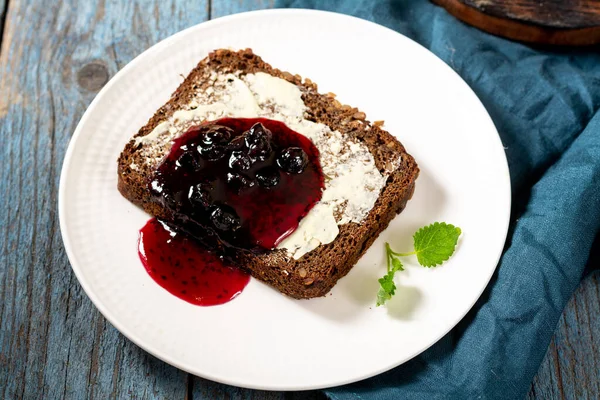 Bread with butter and blackcurrant jam. Rye bread sandwich with sunflower seeds with butter and jam. Breakfast
