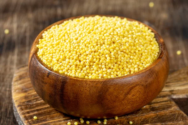 Millet. Millet ahşap bir kaşıkta kase ve ahşap bir mutfak masasında.