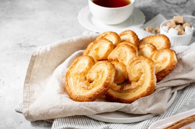 Tüttür. Flaky Sugar Palmiers kurabiyeleri seramik tabakta, arka planda. Tatlı ev yapımı kekler.