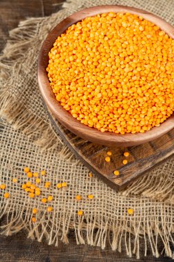 Kahverengi ahşap masadaki ahşap bir kasede kırmızı mercimek.