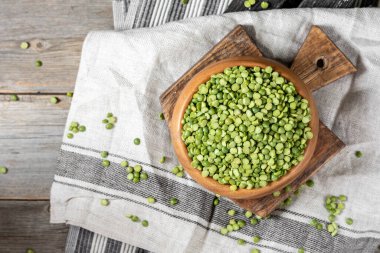 Yeşil bezelyeler. Ahşap bir masada tahta bir kasede kuru yeşil bezelyeler. Organik Doğal Vejetaryen Ürünleri