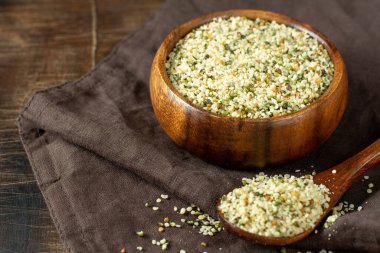 Kenevir tohumları. Ahşap bir masada ahşap bir kasede kurutulmuş kenevir tohumları. Pişirmek için kenevir tohumları