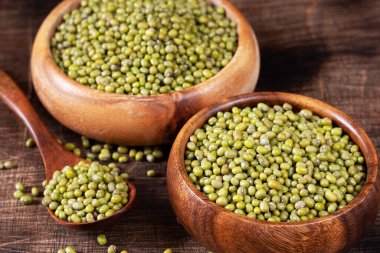 Mung. Kahverengi ahşap bir masada bir kasede yeşil fasulye. Sağlıklı bir diyet için baklagil bitkisi