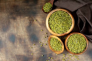 Mung. Kahverengi ahşap bir masada bir kasede yeşil fasulye. Sağlıklı bir diyet için baklagil bitkisi