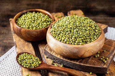 Mung. Kahverengi ahşap bir masada bir kasede yeşil fasulye. Sağlıklı bir diyet için baklagil bitkisi