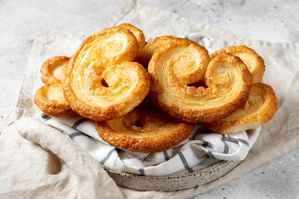 Tüttür. Flaky Sugar Palmiers kurabiyeleri seramik tabakta, arka planda. Tatlı ev yapımı kekler.