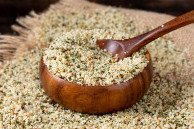 Kenevir tohumları. Ahşap bir masada ahşap bir kasede kurutulmuş kenevir tohumları. Pişirmek için kenevir tohumları