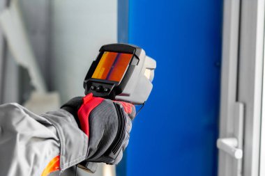 Termal görüntüleme. Bir elektrikçinin elindeki termal görüntüleyici ekipmanları teftiş ediyor.