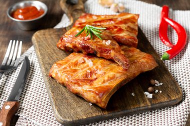 Kahverengi ahşap bir masada ahşap servis tahtasının üzerinde füme domuz kaburgası. Kızarmış domuz pirzolası.