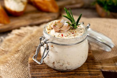 Kahverengi ahşap mutfak masasında cam bir kavanozda tavuk ezmesi. Ahşap arka planda baharatlı ev yapımı tavuk filetosu.