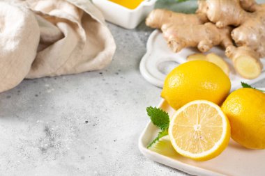 Limonlu, ballı ve naneli zencefilli çay. Limon, zencefil, bal ve açık gri mutfak masasında nane şekeri. Bağışıklık sistemi için sağlıklı yiyecekler. Kopyalama alanı