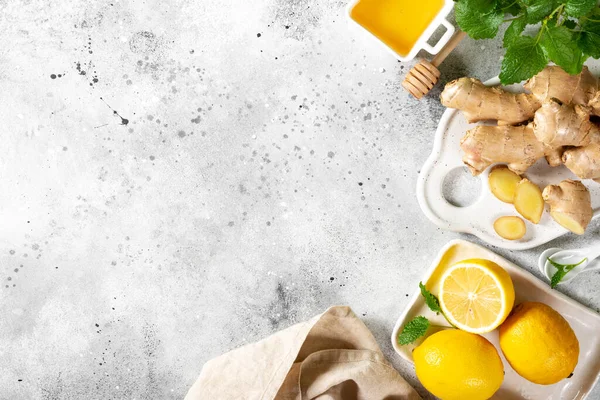 Limonlu, ballı ve naneli zencefilli çay. Limon, zencefil, bal ve açık gri mutfak masasında nane şekeri. Bağışıklık sistemi için sağlıklı yiyecekler. Kopyalama alanı olan üst görünüm