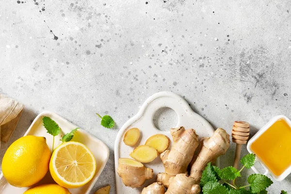 Ingredients for ginger tea with lemon, honey and mint. Lemon, ginger, honey, and mint on the light gray kitchen table. Healthy food for the immune system. Top view with copyspace