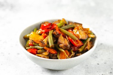 Açık gri mutfak masasında gri bir kasede sebze turşusu. Farklı sebzeler, kırmızı biber, patlıcan, havuç ve bezelye. Vejetaryen yemeği.