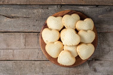 Limonlu kurabiye. Kahverengi ahşap bir masada yuvarlak servis tahtasındaki limonlu kurabiye kalpleri. Sevgililer Günü için kurabiye. Kopyalama alanı olan üst görünüm
