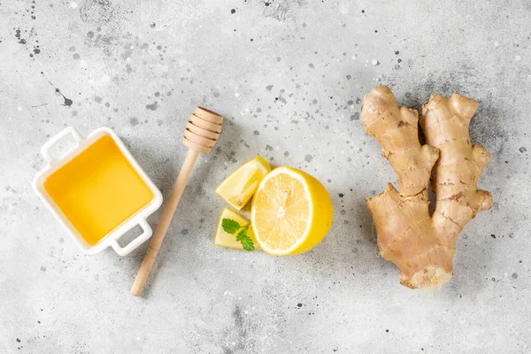 Ingredients for ginger tea with lemon, honey and mint. Lemon, ginger, honey and lemon balm on the table. Healthy food to boost immunity. Ingredients for ginger cookies with honey and mint. Top view