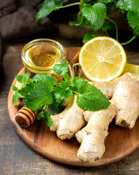 Ingredients for ginger tea with lemon, honey and mint. Lemon, ginger, honey and lemon balm on the table. Healthy food to boost immunity. Ingredients for ginger cookies with honey and mint