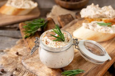 Kahverengi ahşap mutfak masasında cam bir kavanozda tavuk ezmesi. Ahşap arka planda baharatlı ev yapımı tavuk filetosu.
