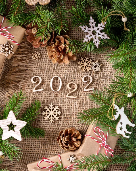 Mutlu yıllar 2022. 2022 numara ahşap zemin üzerinde ahşaptan yapılmıştır. Noel arkaplanı köknar dallarıyla dolu. ECO dekorasyonları