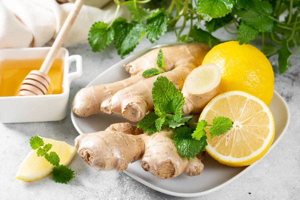 Ingredients for ginger tea with lemon, honey and mint. Lemon, ginger, honey and lemon balm on the table. Healthy food to boost immunity. Ingredients for ginger cookies with honey and mint