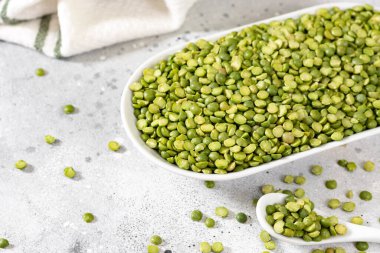Yeşil bezelyeler. Açık gri mutfak masasında beyaz bir seramik kasede kuru yeşil bezelyeler. Organik Doğal Vejetaryen Ürünleri