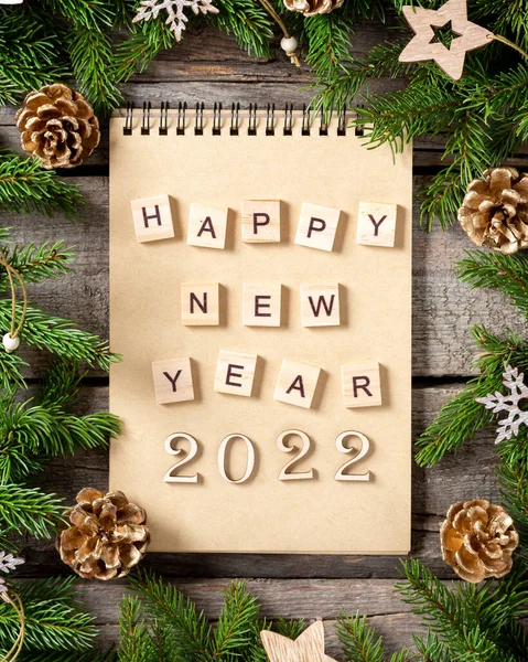 Mutlu yıllar 2022. 2022 numara kahverengi ahşap zemin üzerinde ahşaptan yapılmıştır. Noel arka planında köknar dalları, ahşap dekorlar ve el işi kağıdından hediye kutularıyla süslenir. Düzgünce