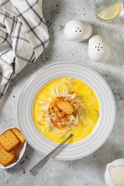 Kremalı et suyunda tavuk göğsü. Sebzeli ve kremalı tavuk. Açık gri mutfak masasında bir kasede tavuk çorbası. Üst görünüm