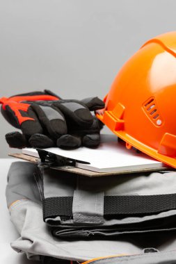 Gri masadaki inşaat malzemeleri. Üniforma, kask, gözlük ve eldiven.