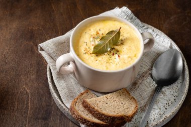 Kremalı tavuk çorbası. Püre çorbası tavuk, havuç ve kremalı soğan çorbası. Kahverengi ahşap bir masada, kasede tavuk çorbası.