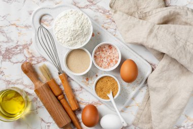 Mutfak zemininde pişirmek için gerekli malzemeler. Yumurta, un, kuru maya, şeker, mutfak masasında tuz. Maya pişirmeye hazırlık konsepti. Üst görünüm 