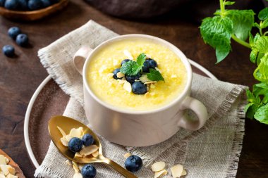 Yaban mersinli ve bademli Polenta yemeği. Kahverengi ahşap mutfak masasında seramik tabakta mısır lapası. Sütlü krema çorbası. Sağlıklı vejetaryen yemekleri