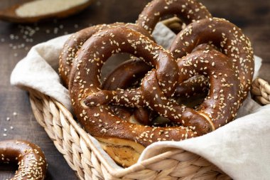 Alman krakeri. Kahverengi ahşap mutfak masasında susamlı krakerler. Brezel sepette. Yakın plan.