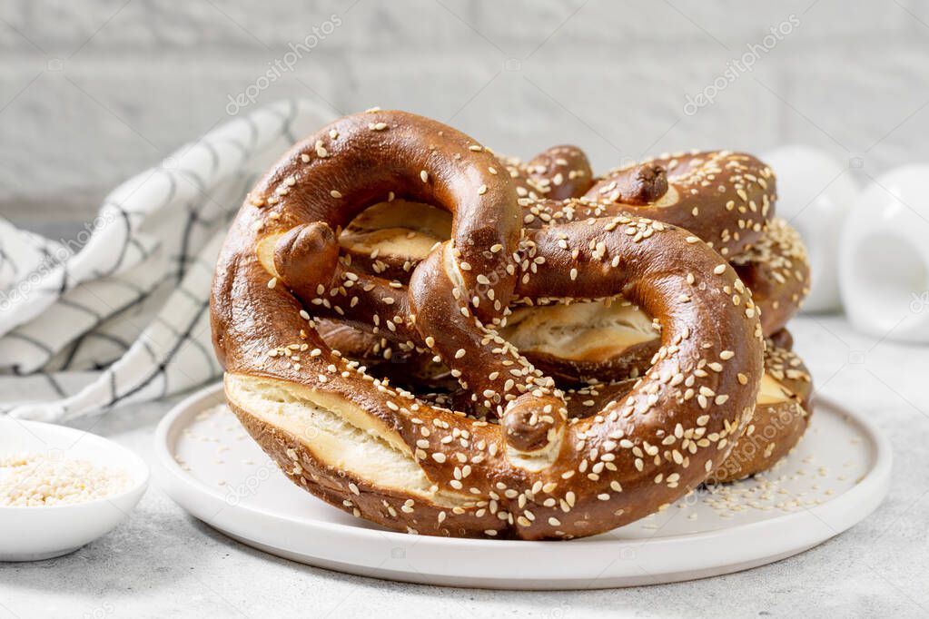 German pretzel. Pretzels with sesame seeds on the light gray kitchen table. Brezel on the table