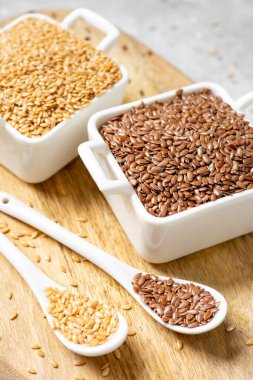 Açık gri arka planda beyaz kaselerde kahverengi ve beyaz keten tohumları. Sağlıklı vejetaryen yemekleri