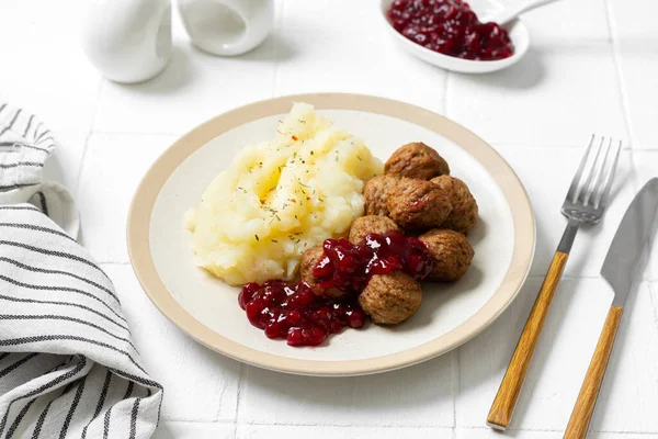 Swedish meatballs with mashed potatoes and lingonberry jam. A traditional Scandinavian dish in a ceramic plate on a white kitchen table