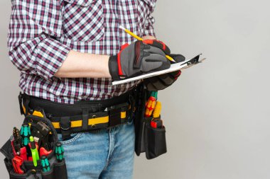 İnşaatçı ya da elektrikçi elinde bir kağıt ve kalem tutuyor. Kurulum çalışmaları için bir sözleşme imzalama kavramı. İnşaat malzemeleri için bir tahmin hazırlama