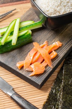 Nori çarşafları. Çıtır çıtır yosun, beyaz pirinç, salatalık ve alabalık servis tahtasında. Suşi ve rulo için malzemeler. Japon geleneksel mutfağı