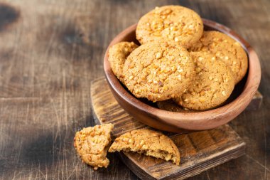 Sağlıklı ev yapımı yulaf ezmeli kurabiyeler. Kahverengi mutfak masasının üzerinde, ahşap bir kasede fıstık var.