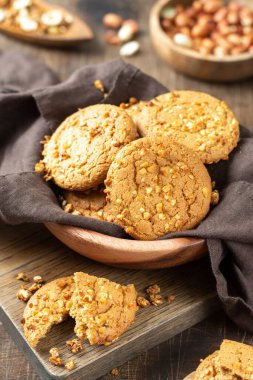 Sağlıklı ev yapımı yulaf ezmeli kurabiyeler. Kahverengi mutfak masasının üzerinde, ahşap bir kasede fıstık var.