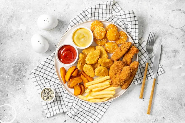 Kipnuggets Strips Frietjes Gebakken Aardappelen Ketchup Kaassaus Een Lichte Ondergrond — Stockfoto
