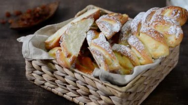 Süzme peynirli tatlı bir çörek ve sepetteki kuru üzümler beyaz mutfak masasının üzerine pudra şekeri serpiştirilir. Ev yapımı yüksek kalorili pişirme konsepti
