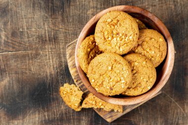 Sağlıklı ev yapımı yulaf ezmeli kurabiyeler. Kahverengi mutfak masasının üstünde, üzerinde yer fıstığı var.