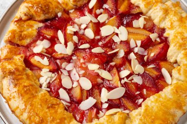 Fransız Galerisi ya da parlak mutfak masasında seramik tabakta kırmızı erikler ve bademli bir turta. Yaz geleneksel ev yapımı tatlı hamur işleri