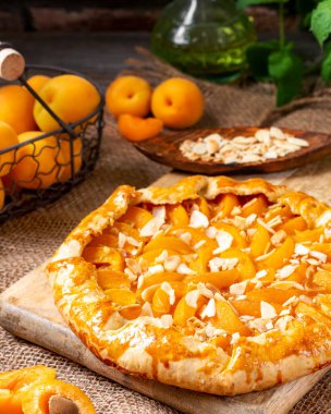  Fransız Galerisi ya da kayısı ve bademli bir turta kahverengi mutfak arka planındaki ahşap servis panosunda. Yaz ev yapımı tatlı hamur işleri