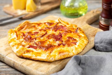 Gri ahşap mutfak arka planında servis panosunda hindi eti, parmesan peyniri ve mozzarella peynirli turta. Nefis ev yapımı, doyurucu hamur işleri.