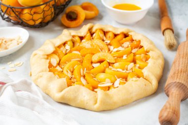 Fransız galeti ya da kayısı ve bademli turta yapma süreci. Hafif bir mutfak arka planında yaz pişirme malzemeleri